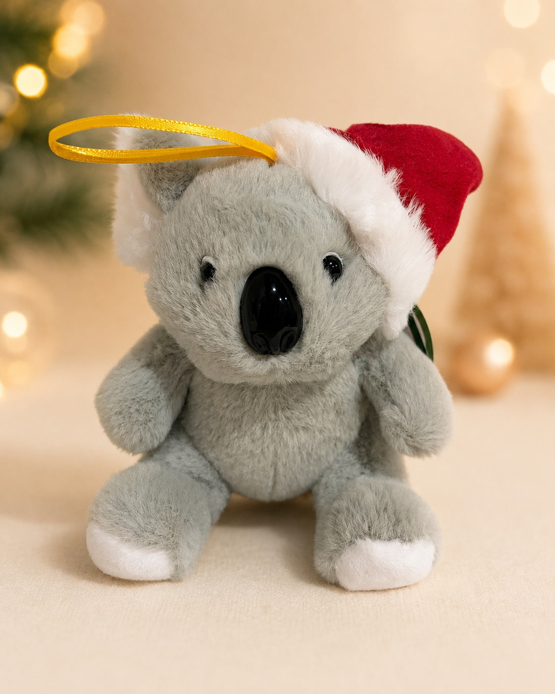 Grey koala plush in a Santa hat with a yellow ribbon hanging loop